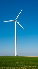Fototapeta premium White wind turbine against bright blue sky and green field, clean energy concept.