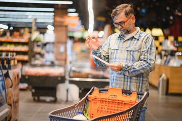 Shocked man looking at fiscal receipt in grocery store