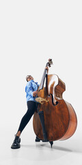Elegant jazz female bassist with long hair flowing, embracing sound and rhythm in powerful musical expression on white background. Concept of music, performance, jazz, concert, passion, instruments.