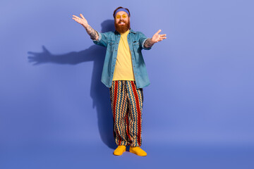 Fototapeta premium Stylish bearded man in vibrant casual wear posing on a purple background with a cheerful expression