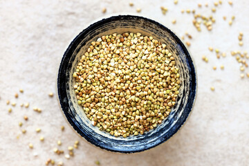 Hulled buckwheat grains in a rustic bowl against light stone background