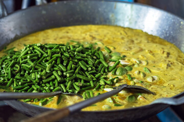 Yardlong bean or Vigna sinensis also call green beans fillet in spicy coconut sauce green curry in large cooking pan on stove. Green curry with vegetable. Thai cuisine. Vegetable pan, Selective focus.