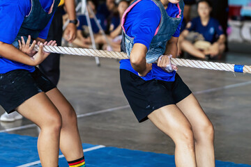 Female students participate in tug of war match. Young woman playing active games pulling rope in...