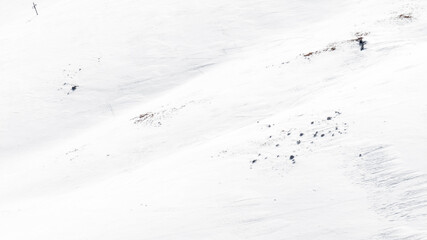 Aerial view of snowy mountain terrain. Snow completely covers the ground. Ideal for texture, pattern and background.