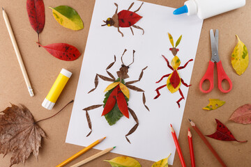 A delightful nature-themed craft project with colored leaves forming insect designs on white paper. Perfect for schools, craft workshops, and art supply businesses focused seasonal DIY projects.