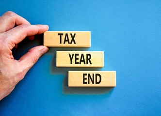 Tax year end symbol. Concept words Tax year end on beautiful wooden blocks. Beautiful blue background. Businessman hand. Business tax year end concept. Copy space.
