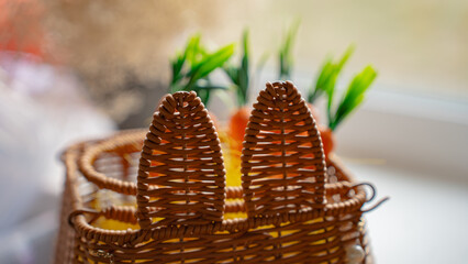 Easter basket with bunny ears decorated, with a carrot inside.