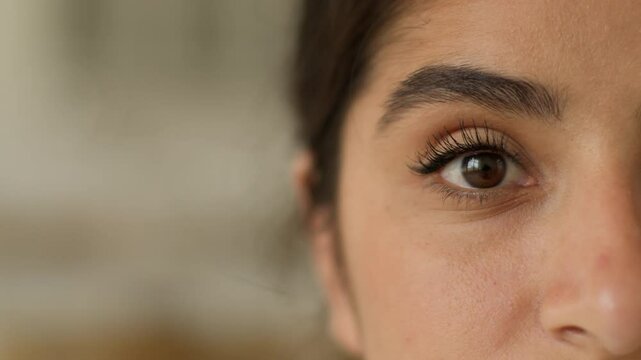 Extreme close up half face calm dark eye Indian Arabian woman cropped view healthy girl female look gaze health medicine clinic laser correction ophthalmology looking at camera eyesight make-up indoor