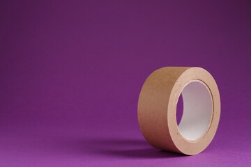 Roll of masking tape on violet background, space for text