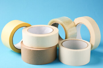 Rolls of different adhesive tapes on light blue background, closeup