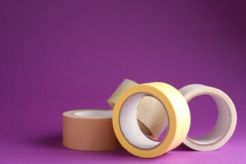 Rolls of different adhesive tapes on purple background