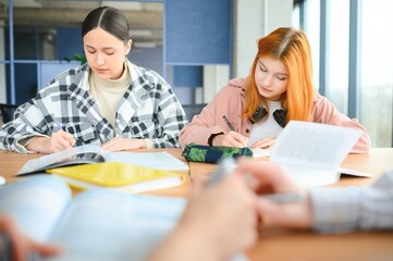 Obraz premium students sit at shared desk making notes studying together at university