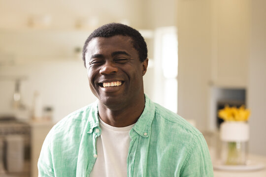 Smiling African American man in green shirt enjoying time at home, feeling relaxed and happy