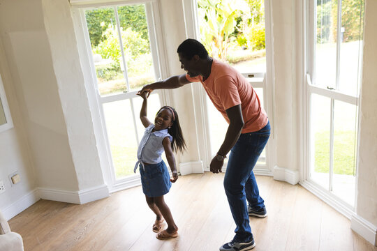 African American father and daughter dancing joyfully at home, enjoying quality time together