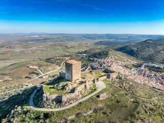 Aerial view of Feria castle in Spain, Gothic and Mudéjar style buildings, square keep, blue sky...