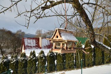 Handmade wooden birdhouse in the garden in winter near the house