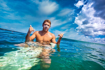 Male surfer in an ocean at sunny day
