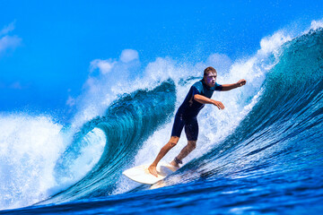 Male surfer on a blue wave at sunny day