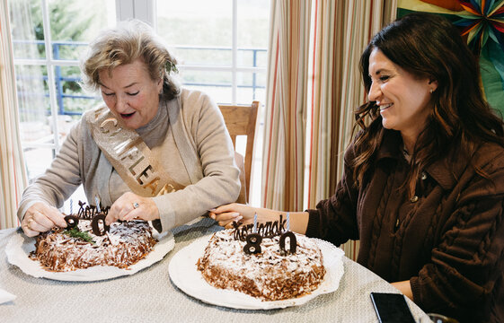 Mother and daughter smiling at 80th birthday celebration - Powered by Adobe