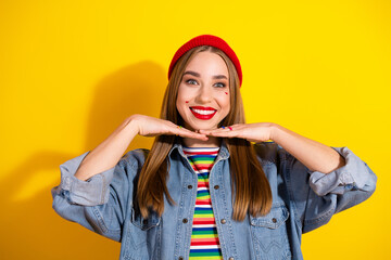 Cheerful young woman in stylish casual outfit posing against bright yellow background, emanating charisma and positivity