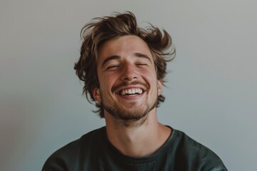 Fototapeta premium Portrait of a glad caucasian man in his 20s laughing over minimalist or empty room background