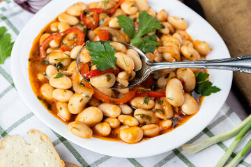 Lobio is a dish of Georgian, Azerbaijani and Armenian cuisines made from green bean pods. Lobio on a spoon. Traditional Georgian cuisine lobio. Lean dish. Lobio with pepper, onion. Side view.