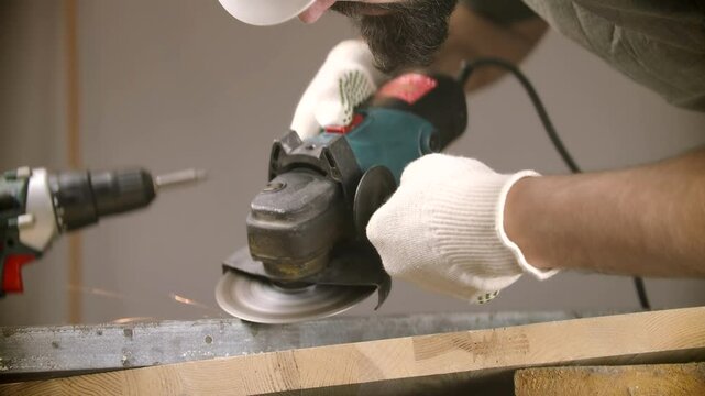 Worker operating power tool while grinding metal surface in workshop