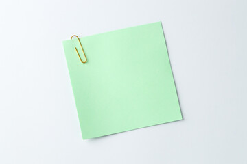 Paper note with clip on light background, top view. Space for text