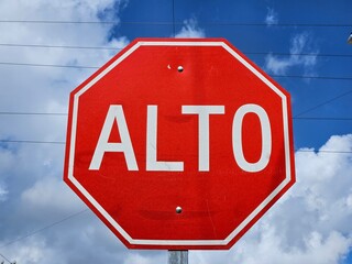 Red Spanish stop sign against a blue cloudy sky