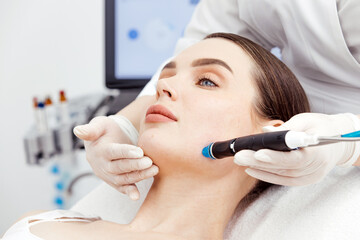 A woman receiving a hydrafacial treatment in a beauty salon. Concept of effective hydration and...