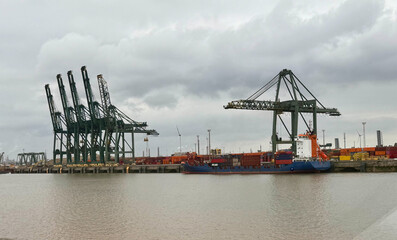 Fototapeta premium View of a port terminal with cranes for moving containers and a cargo ship