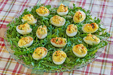 deviled eggs topped with paprika served on a bed of arugula