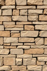 Obraz premium Tan Stone Wall Background Featuring Various Shapes and Sizes of Stones