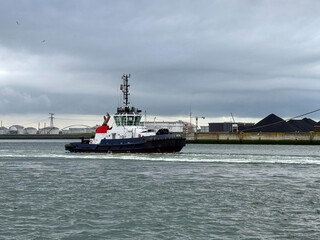 a tugboat, a small, powerful vessel used to maneuver larger ships, often assisting them with docking or navigating in confined waters.