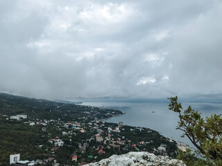 Fototapeta premium Imagine witnessing a breathtaking view of a vibrant cityscape from a high cliff that dramatically overlooks a sparkling body of water, offering a perfect blend of nature and urban life