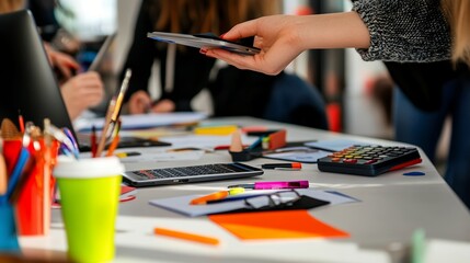 Hand holding tablet over a creative workspace with diverse tools