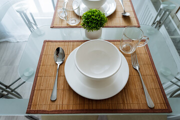 On the surface of a wooden table, there is a variety of tableware including plates, bowls, spoons,...