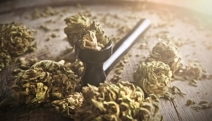 Dried cannabis hemp flowers for smoking rich in CBD on a wooden plate with a smoking pipe, close up...