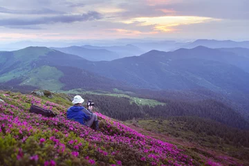 Fototapete Rund Landscape photographer taking a shot of blooming rhododendrons on a summer mountain meadow. Soft sunrise glow © Ivan Kmit