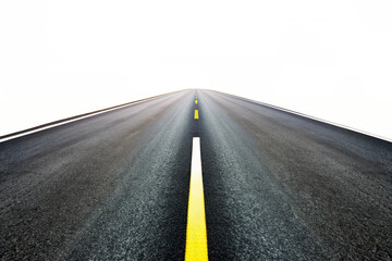 Fototapeta premium A long asphalt road stretching towards a bright horizon with yellow and white lane markings, surrounded by green fields and a partly cloudy sky