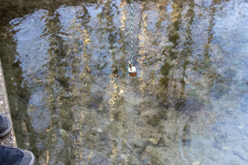 Padlock hanging above clear water, Augsburg, Siebenbrunn, Germany, March 2025