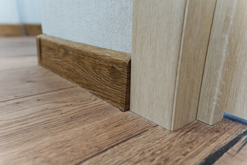 The room features an elegant wooden floor and stylish skirting board, complemented by a beautifully crafted door, creating a warm and inviting atmosphere for all who enter