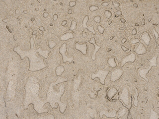 Textura de arena con marcas de agua, creando una imagen abstracta.