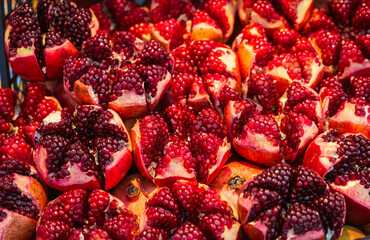 Close-up of freshly cut pomegranates with vibrant red seeds. This juicy fruit is popular for its antioxidants, health benefits, and refreshing taste, often used in juices and desserts.