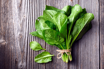 Bunch of fresh just washed green spinach leaves on wooden table close up. Organic spinach greens...