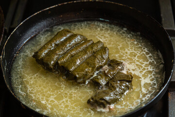Homemade dolma with meat is stewed in a frying pan in broth