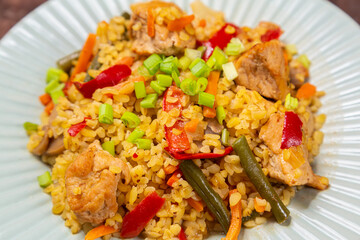 On a wooden table in a plate there are vegetables stewed