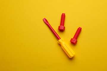 Children's toy screwdriver on a yellow background