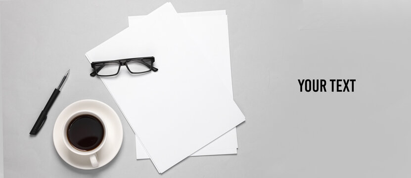 White blank sheets of a4 paper size or documents mockup with pen, eyeglasses and coffee cup on a gray background. Template for design. Top view. Copy space for your text and information