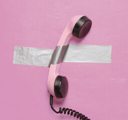 Retro phone tube fixed with adhesive tape on pink background. Conceptual pop, contemporary art